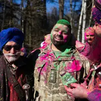 Three Sikh men are pictured covered in neon powder, the man in the middle is wearing British Army uniform.